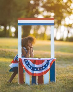 Girl standing in a garden with USA themed stand