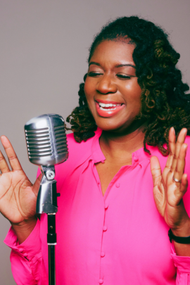 Saundi Harrison-Cooksey with a pink shirt performing in front of a microphone