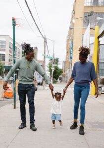Happy family bonding while walking on a city sidewalk holding hands under the sun.