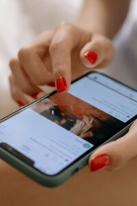 A person with red nails using a smartphone with a touch screen interface